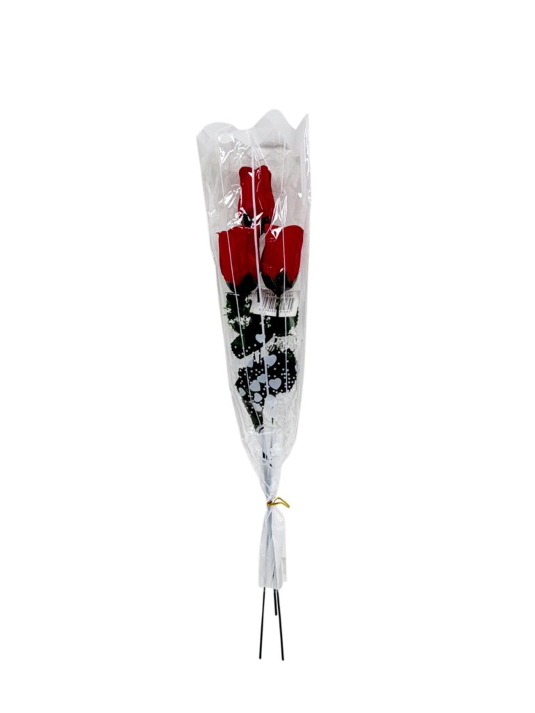 Three red roses wrapped in clear cellophane with white heart-patterned design, tied at the bottom for gifting